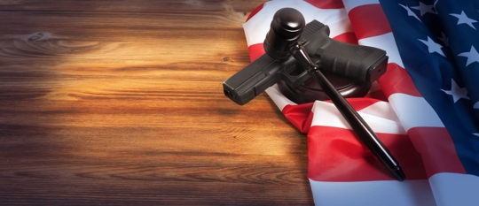 Gavel holding down a gun against American flag